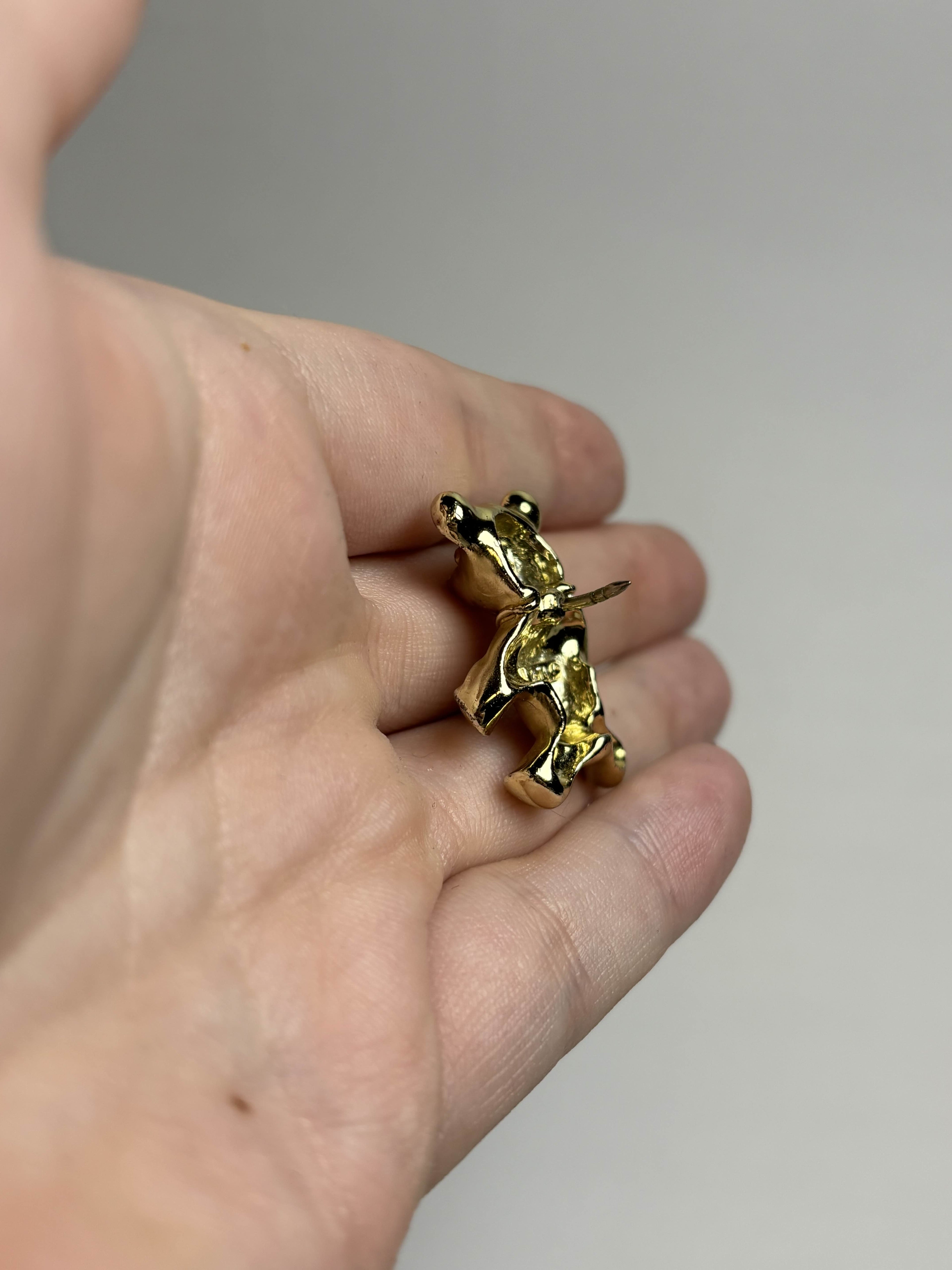 Back of old teddy bear pin showing pin held in a hand against a neutral background