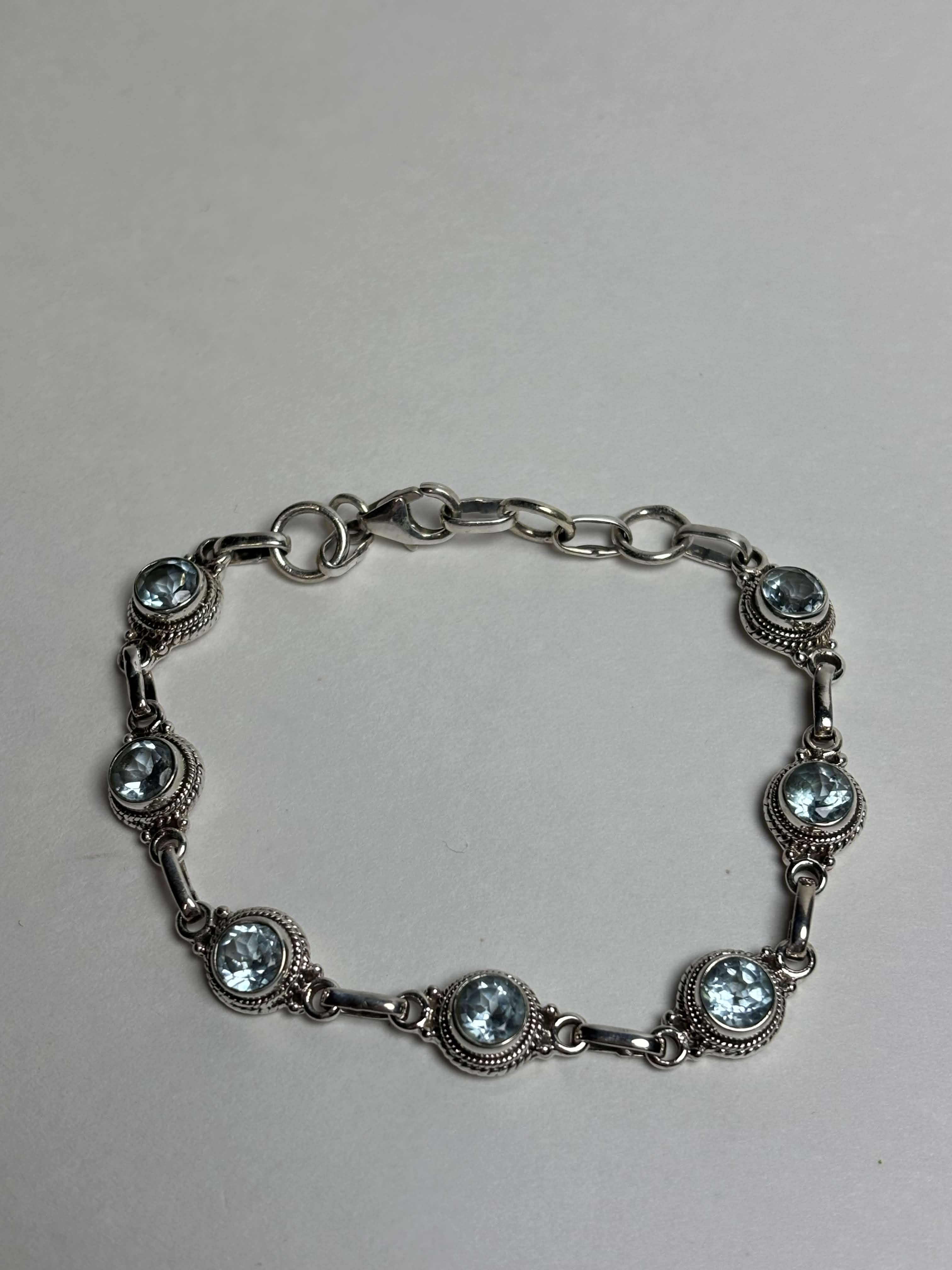Silver bracelet with round light blue gemstones on a neutral background