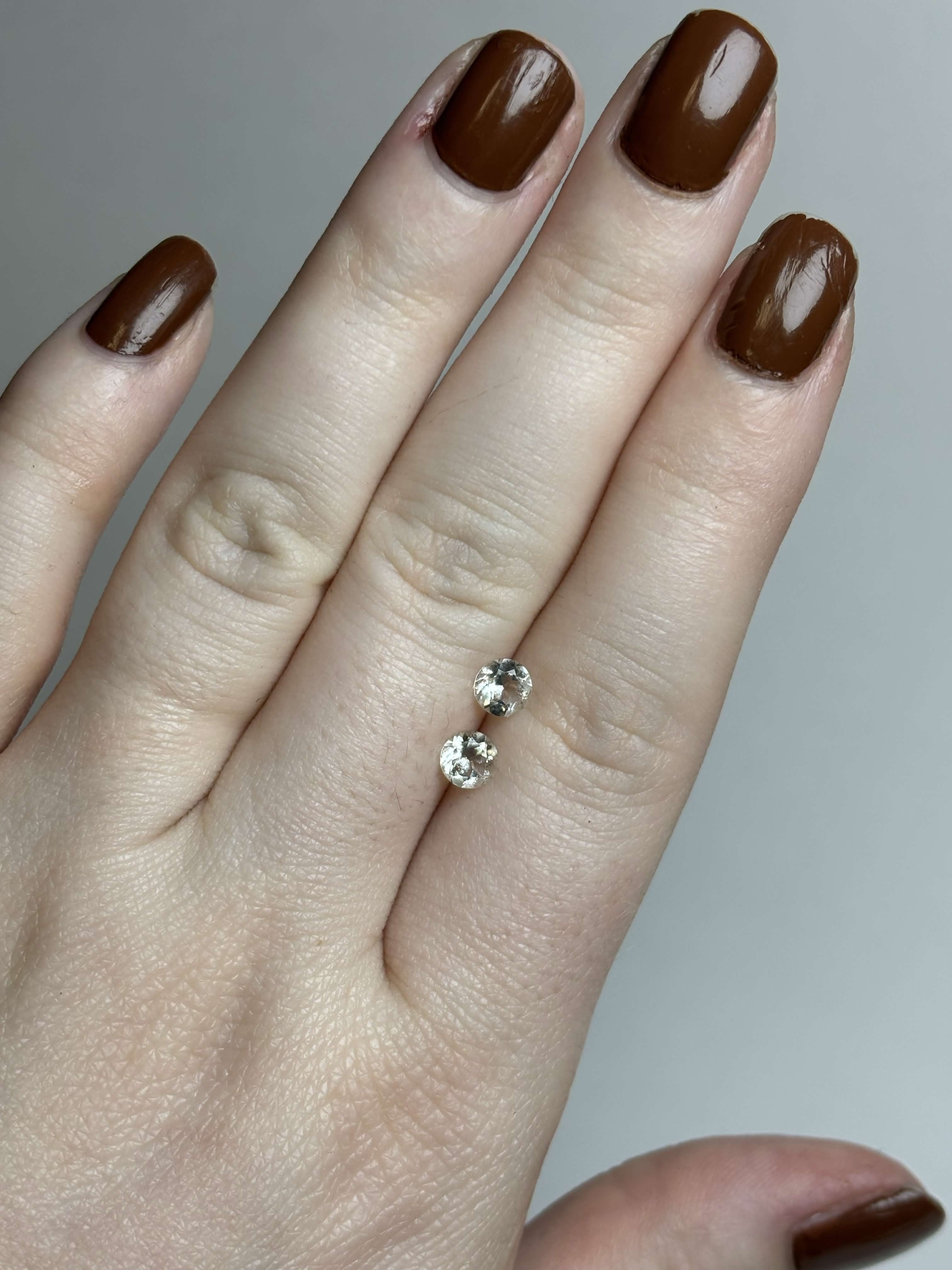 Two round pale green stones on a hand