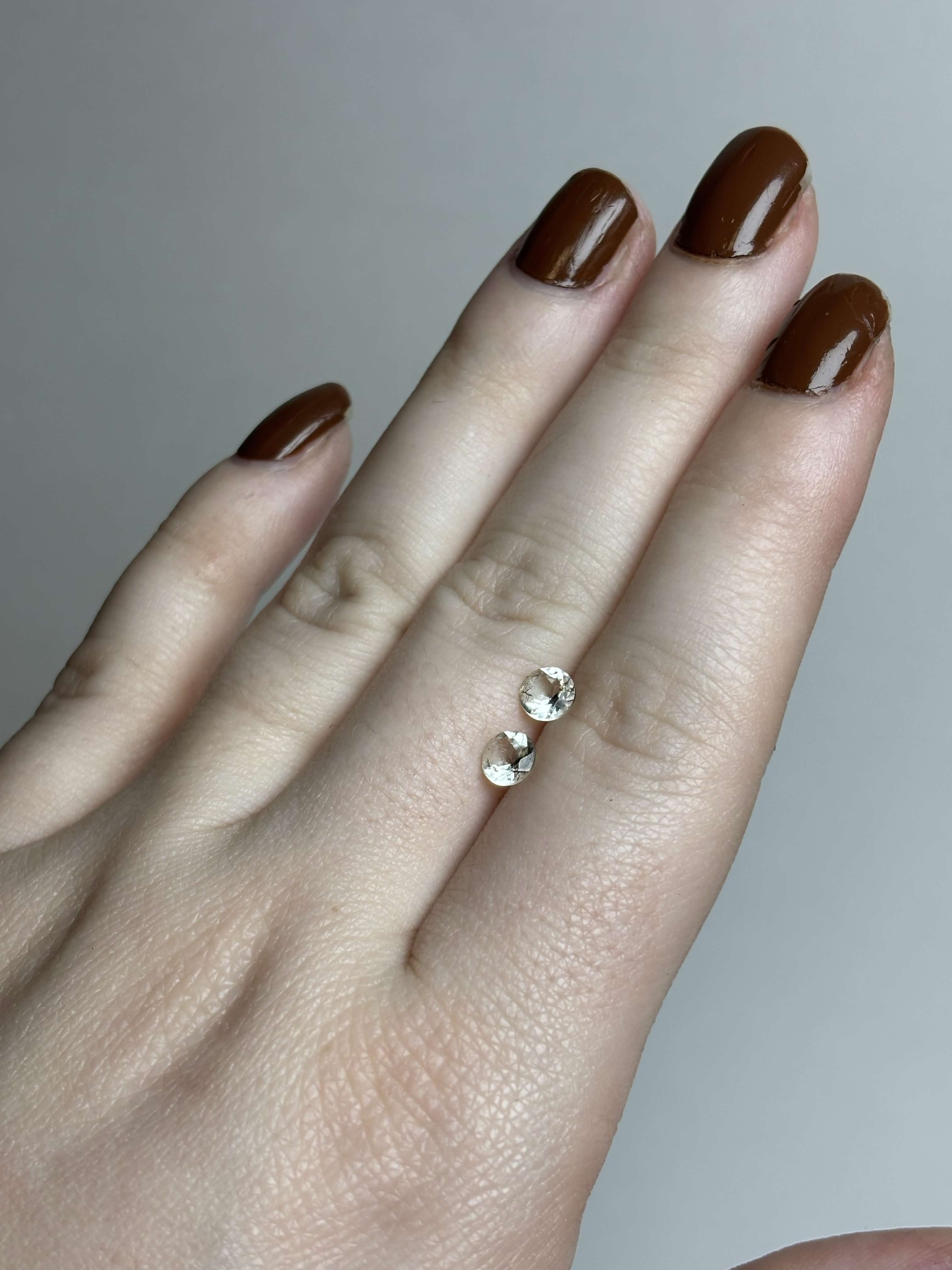 Two round pale green stones on a hand