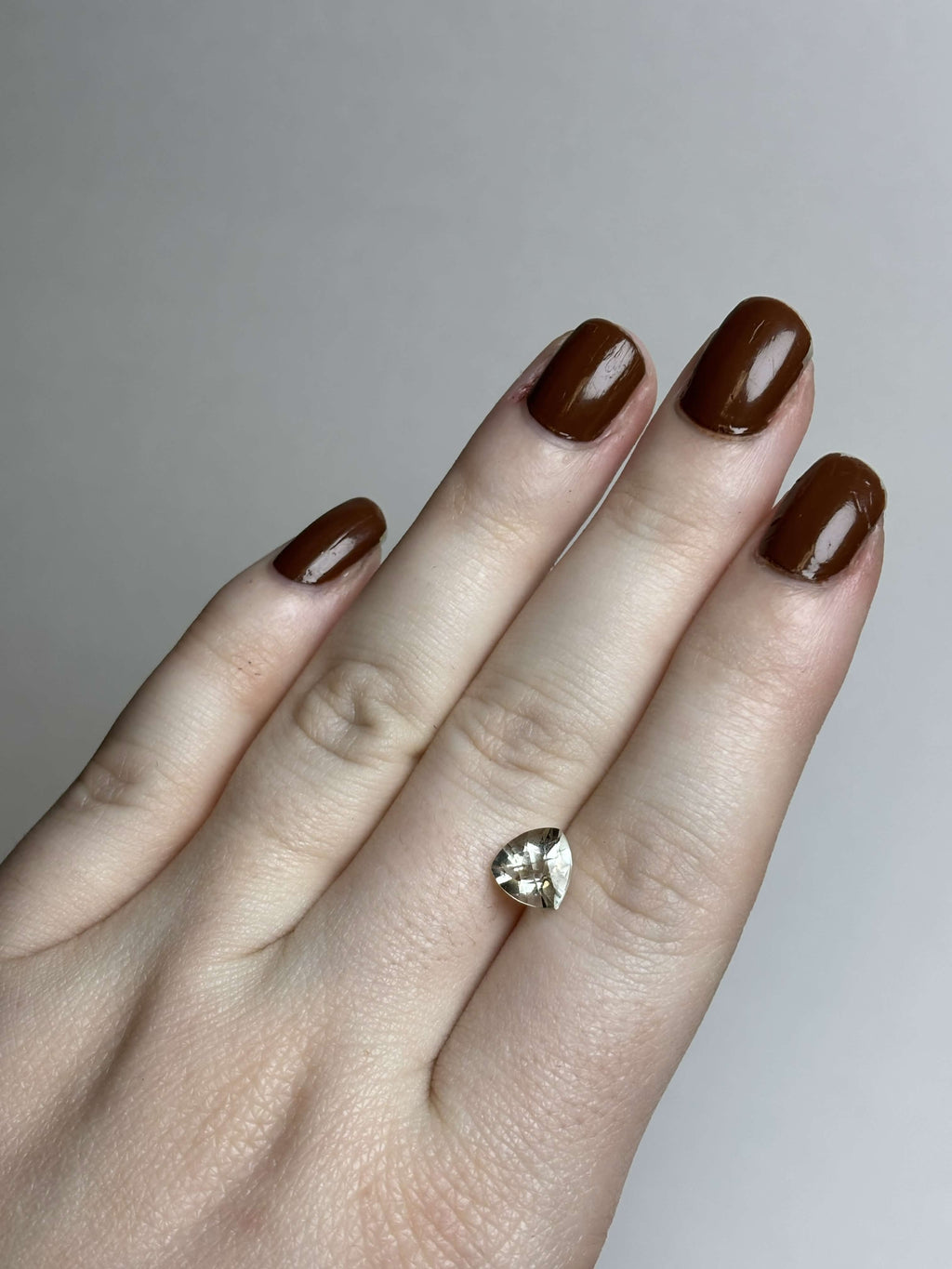 Hand with trillion cut (triangular) light green stone 8 mm in size on it