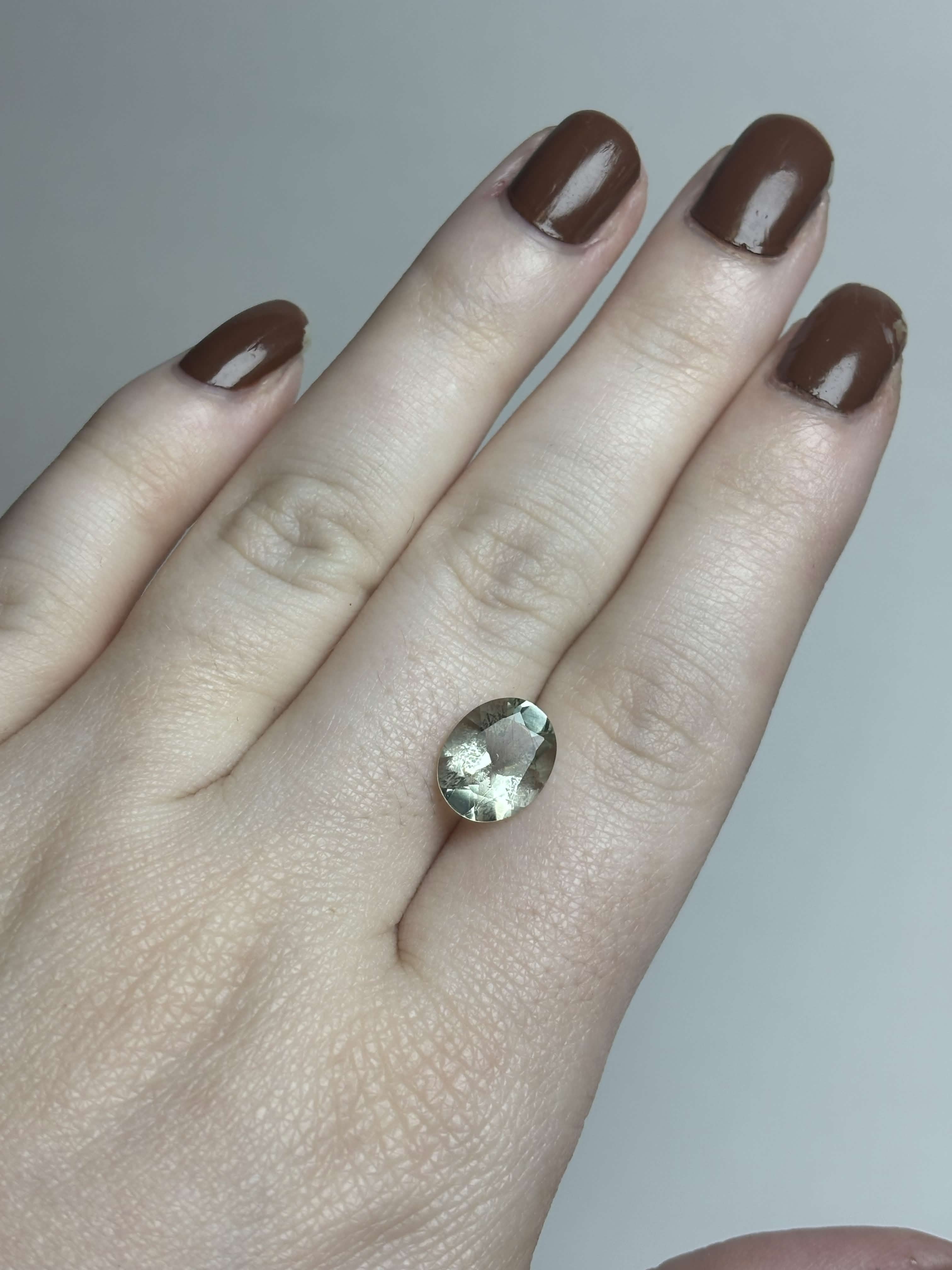Pale green faceted stone on hand