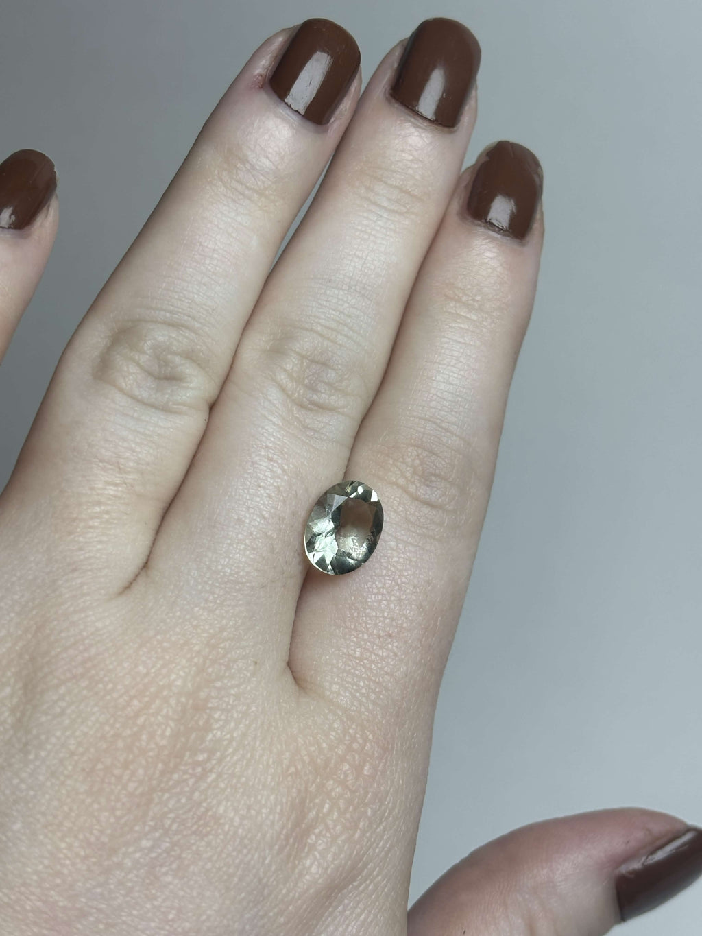 Pale green faceted stone on hand