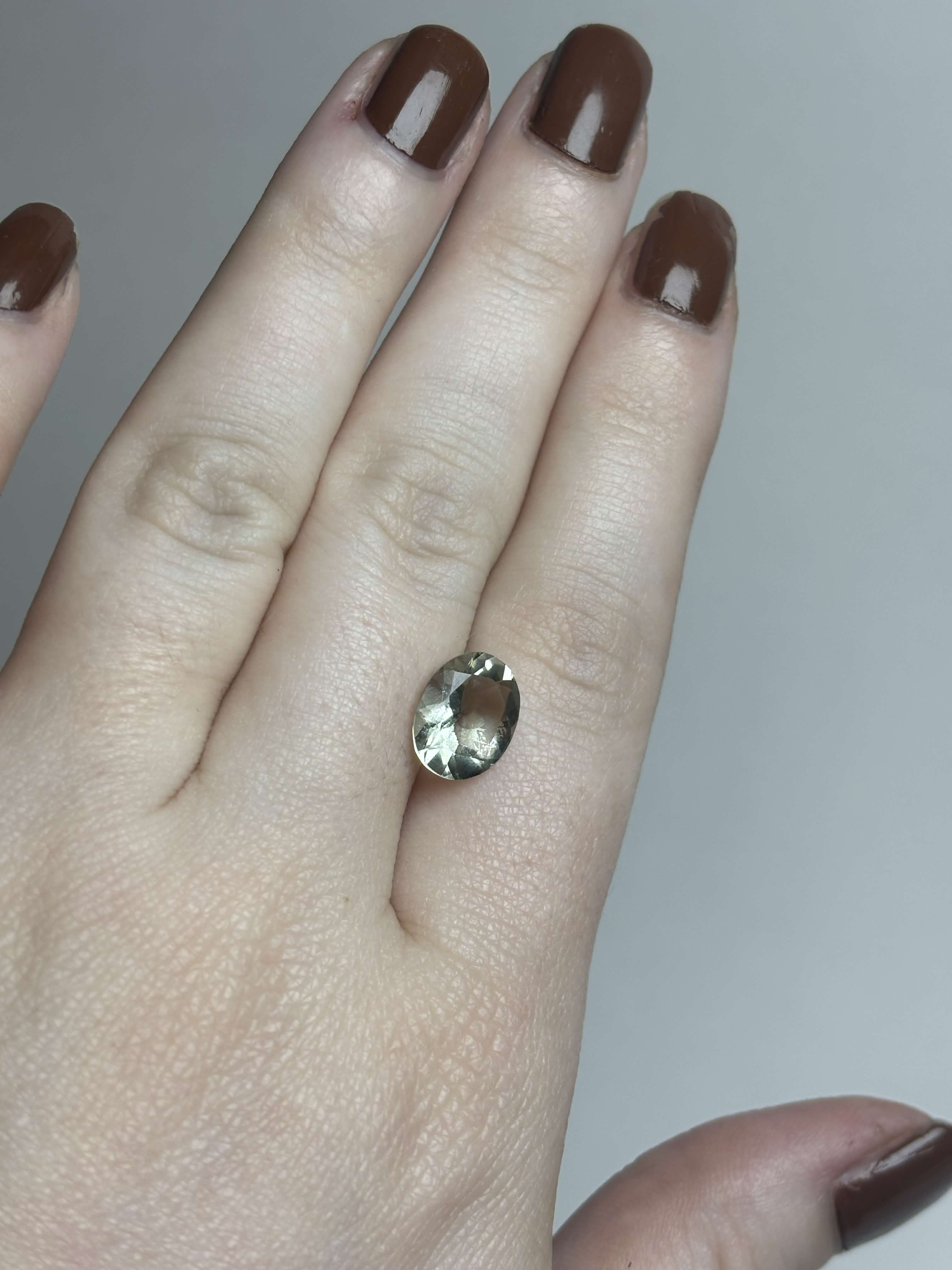 Pale green faceted stone on hand