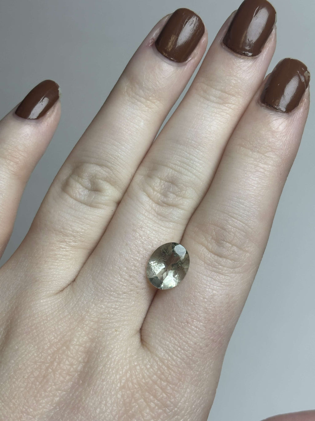 Pale green faceted stone on hand