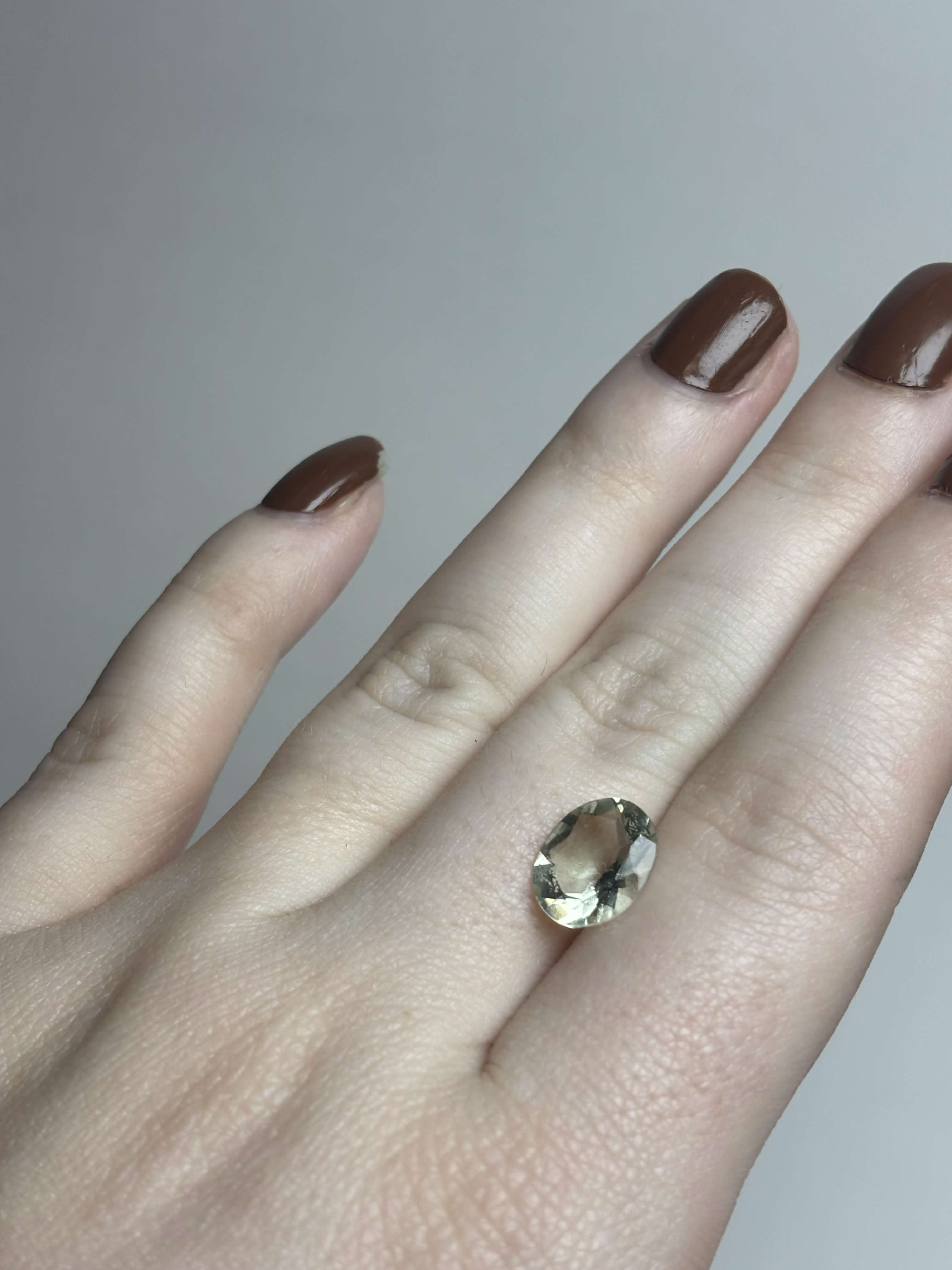 Pale green faceted stone on hand