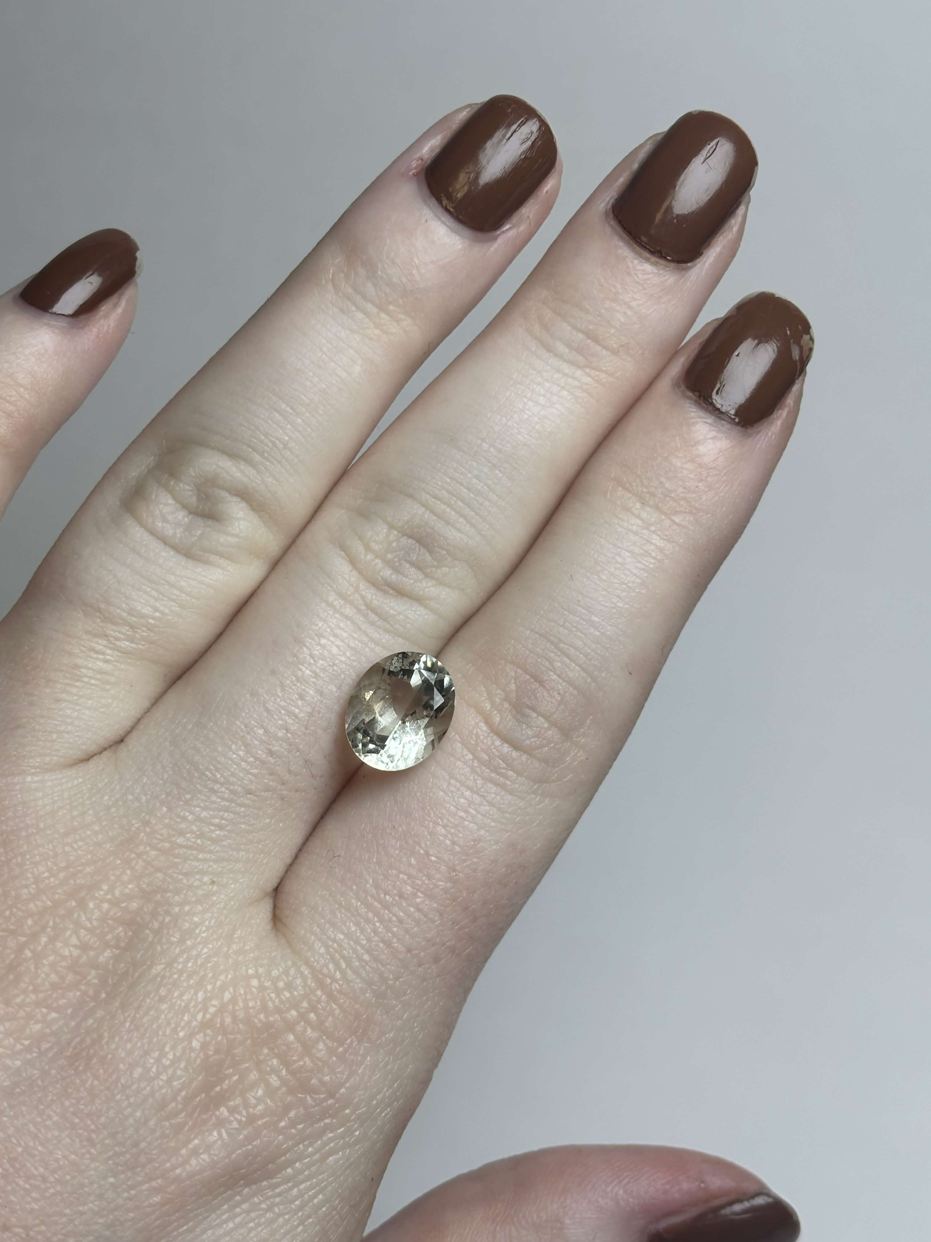 Pale green faceted stone on hand