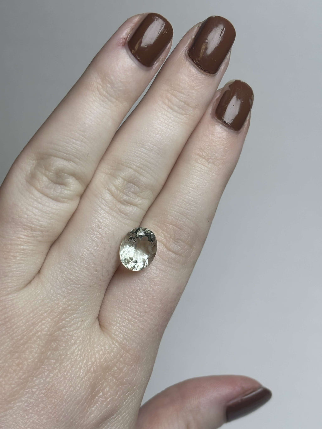 Pale green faceted stone on hand