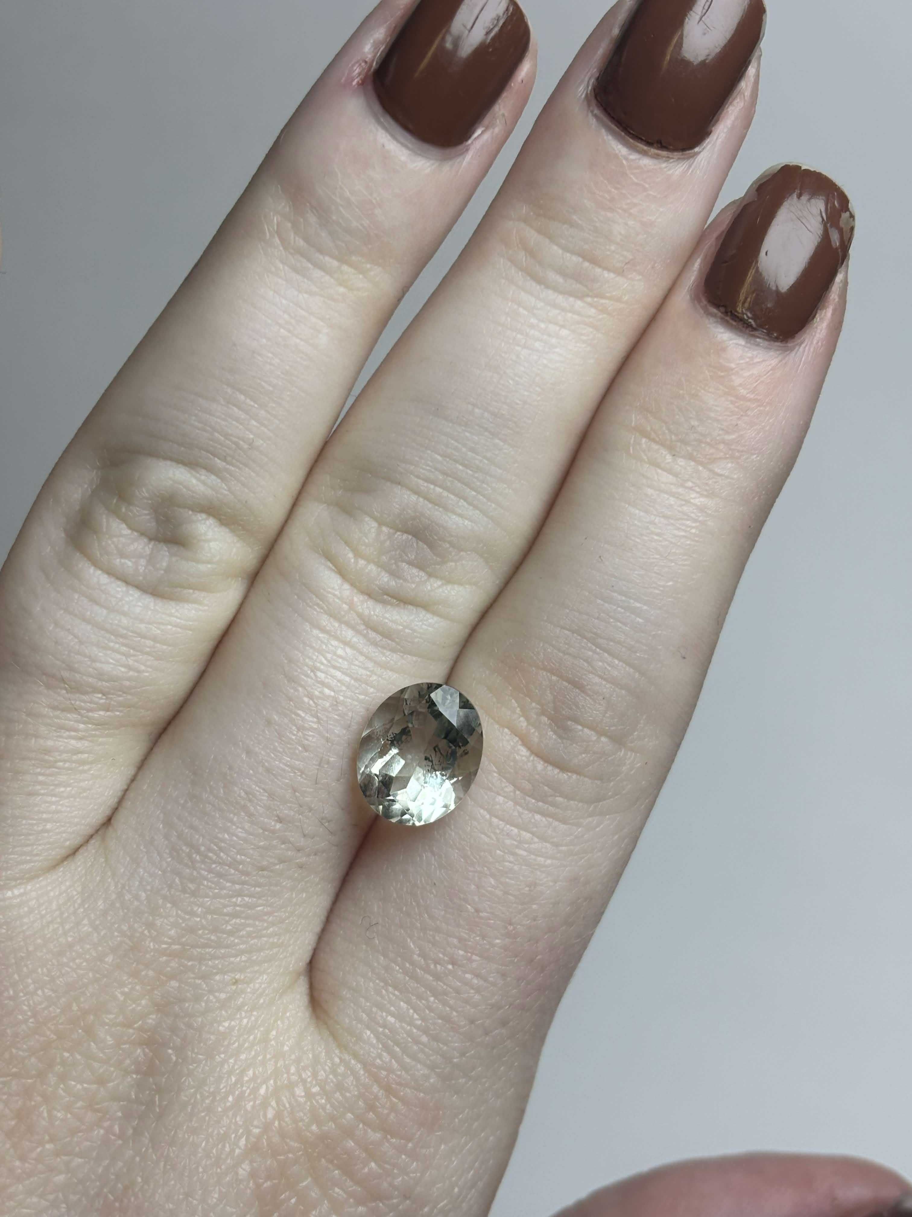 Pale green faceted stone on hand